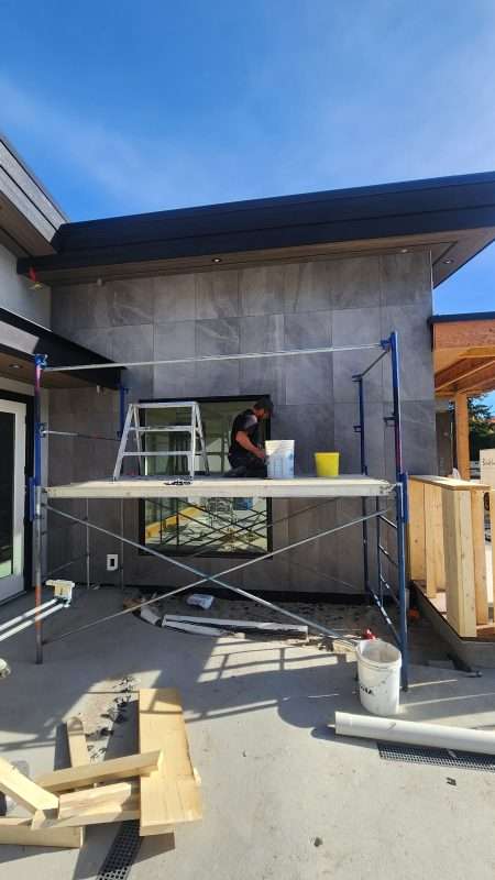 Sierra Flooring installer applying large-format exterior wall tile on a modern home