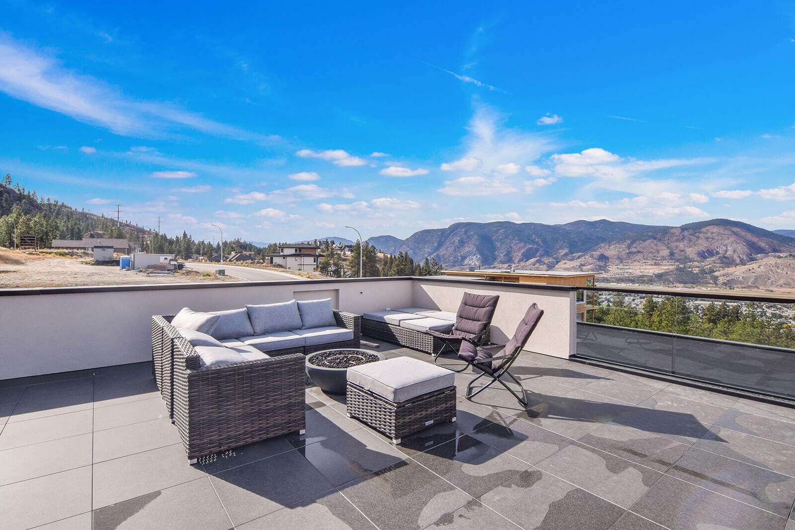 Rooftop patio with 2cm porcelain deck tiles on pedestals, outdoor lounge furniture and Okanagan mountain views