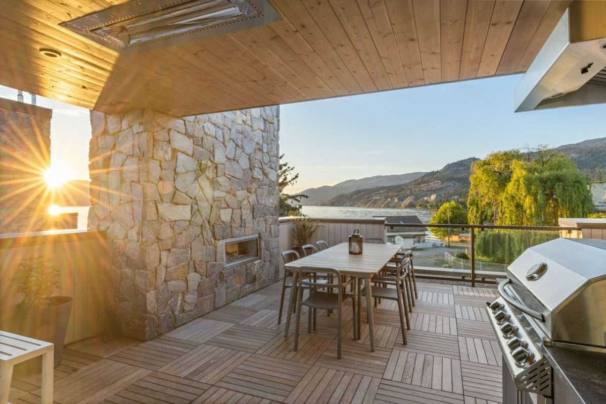 Covered outdoor patio with natural ledgestone wall, wood-look 2cm deck tiles, dining area and BBQ